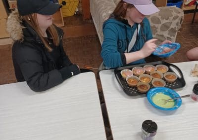 Two young people icing a tray of cupcakes