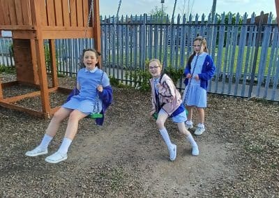 Three children larking about on the swings after school