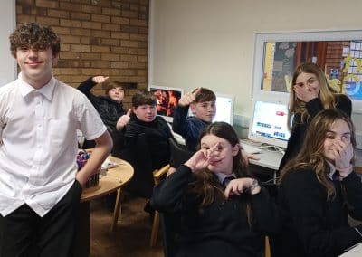 A group of teenagers messing about for the camera in the youth club room
