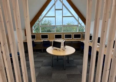Computers set out along the wall beneath a tall gable window