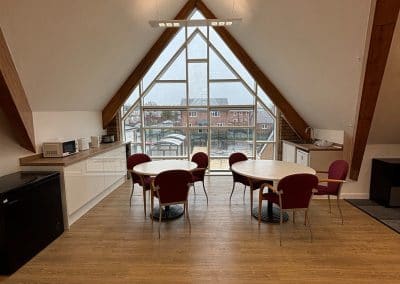 Tables and chairs by the events room’s arched window, with a kitchen counter alongside