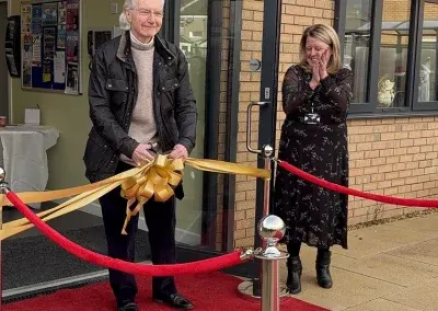 Cutting the gold ribbon across the entrance of the centre, watched by a delighted member of staff.