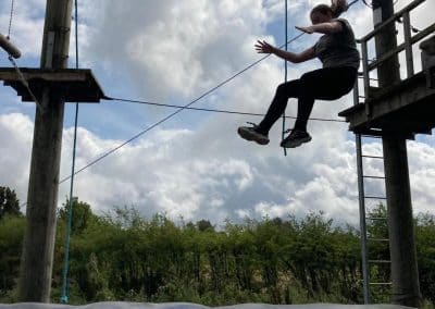 A young person swinging out on the high ropes zip wire