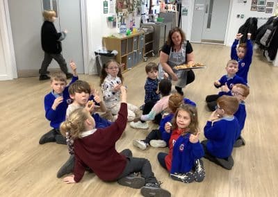 Younger children sitting on the hall floor as a youth worker brings over a tray of food